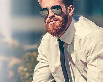 Stylish man with well-groomed beard wearing sunglasses and white shirt demonstrating beard care tips for cold weather protection